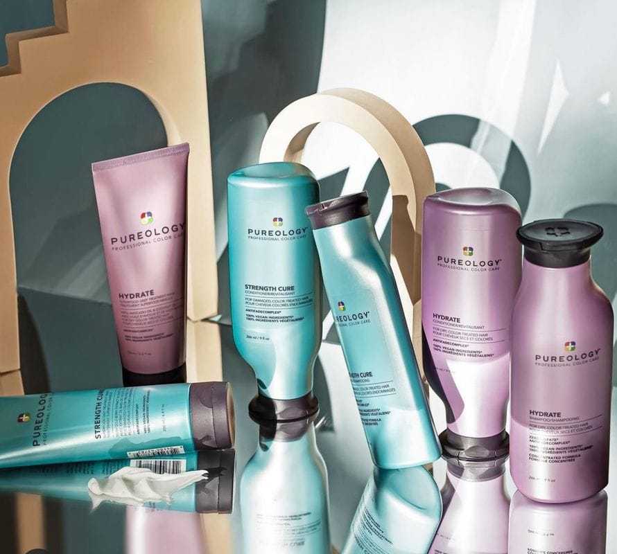 Pureology haircare products on a reflective surface with geometric backdrop.